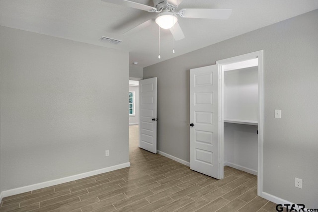unfurnished bedroom with baseboards, a ceiling fan, visible vents, and wood finished floors
