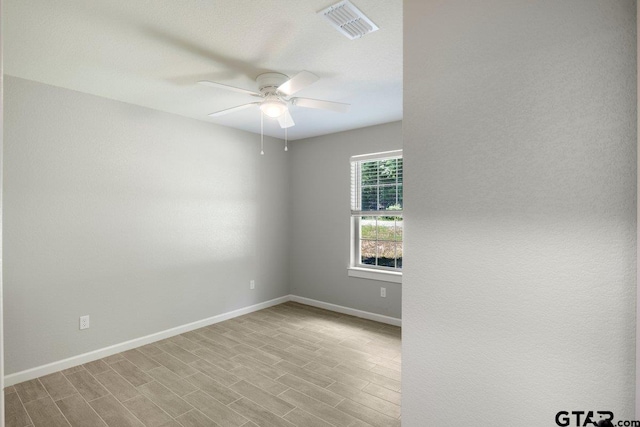 empty room featuring baseboards, a ceiling fan, visible vents, and wood finished floors