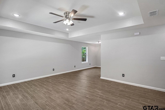 unfurnished room featuring dark wood finished floors, visible vents, baseboards, and a ceiling fan