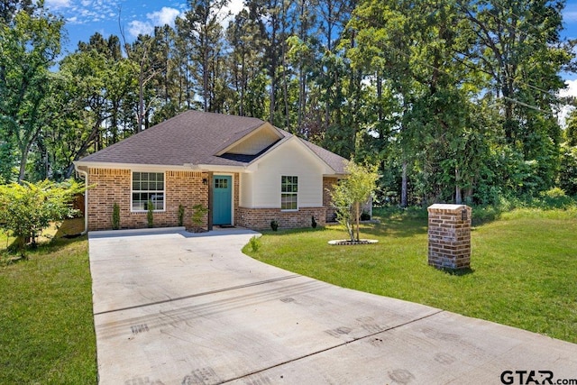 ranch-style house with concrete driveway, roof with shingles, brick siding, and a front lawn