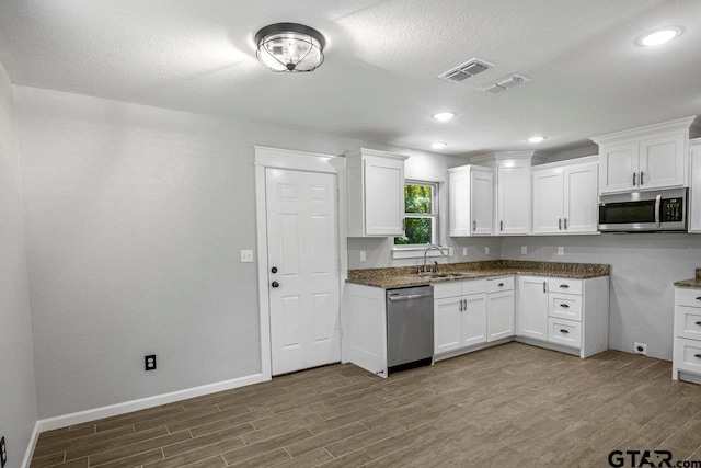 kitchen with stainless steel appliances, baseboards, visible vents, and wood finished floors