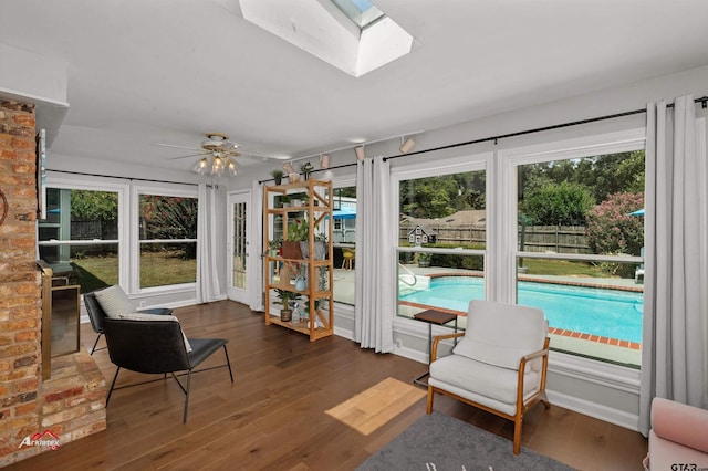 sitting room featuring dark wood-type flooring, ceiling fan, and a skylight