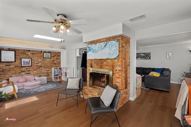 living room featuring wood-type flooring, a brick fireplace, and ceiling fan