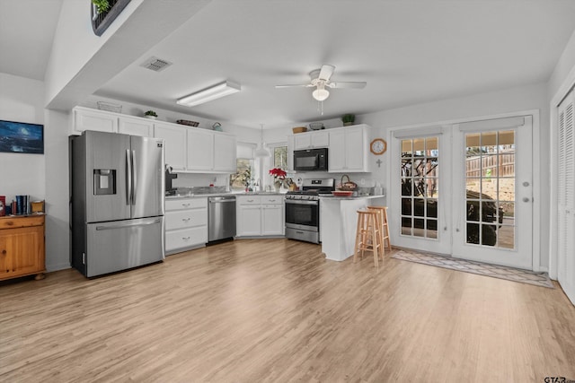 kitchen with ceiling fan, white cabinets, stainless steel appliances, and light hardwood / wood-style flooring