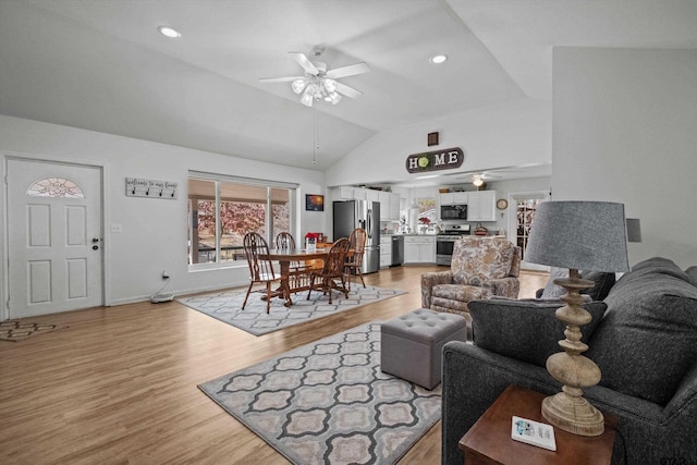 living room featuring ceiling fan, light hardwood / wood-style floors, and vaulted ceiling