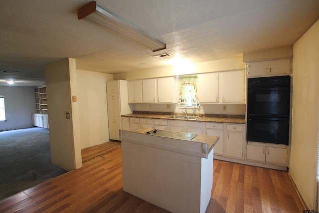 14832 Fm 2661, Flint, TX 75762 - kitchen with a sink, wood finished floors, white cabinetry, a center island, and a textured ceiling