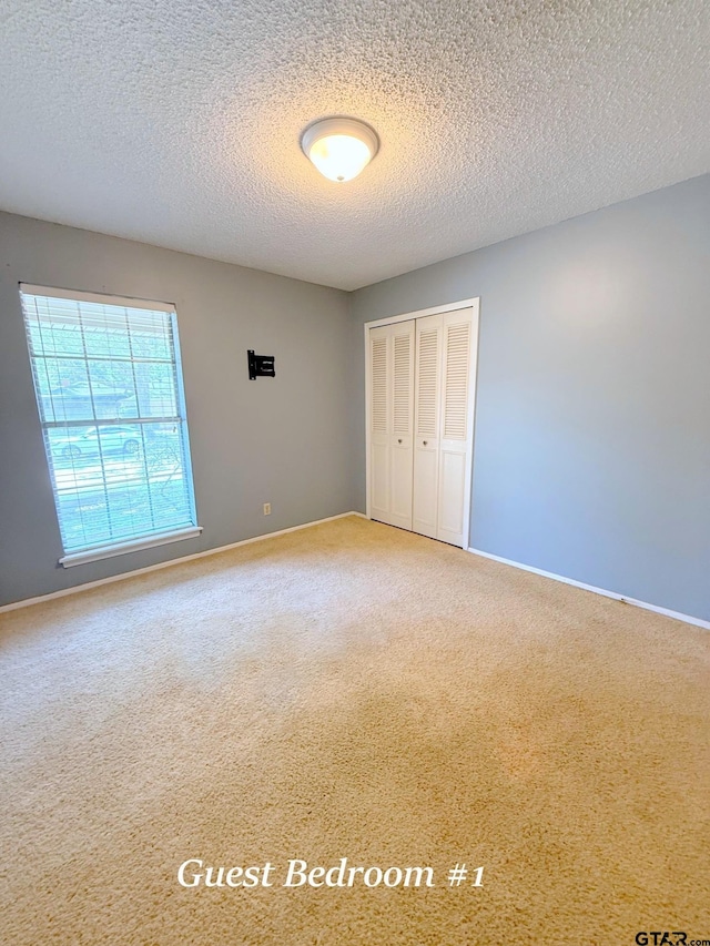 3900 S Donnybrook Ave, Tyler, TX 75703 - unfurnished bedroom with carpet, a closet, a textured ceiling, and baseboards