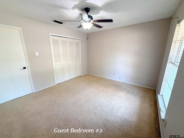 3900 S Donnybrook Ave, Tyler, TX 75703 - unfurnished bedroom with carpet floors, multiple windows, a closet, a textured ceiling, and a ceiling fan