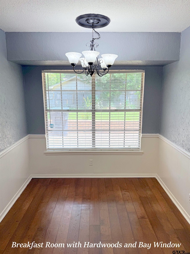 3900 S Donnybrook Ave, Tyler, TX 75703 - unfurnished dining area featuring hardwood / wood-style flooring, healthy amount of natural light, a chandelier, a textured ceiling, and a wainscoted wall