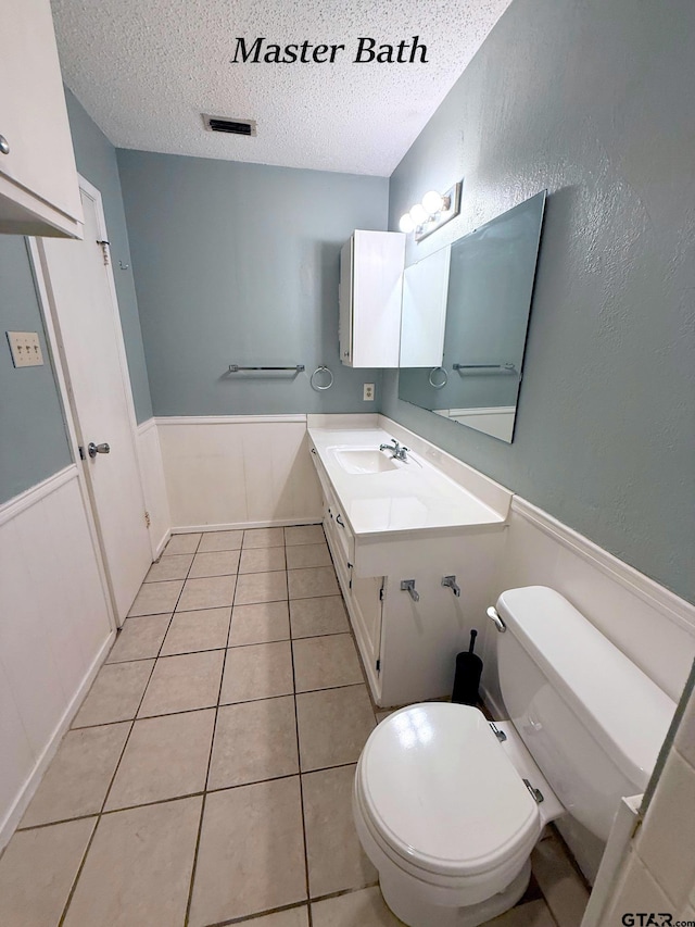 3900 S Donnybrook Ave, Tyler, TX 75703 - bathroom featuring a textured ceiling, a wainscoted wall, vanity, toilet, and tile patterned flooring