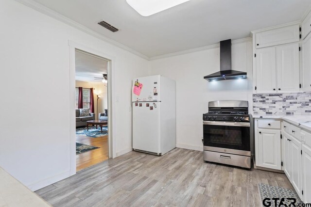 1135 E Sixth St, Tyler, TX 75701 - kitchen featuring freestanding refrigerator, stainless steel gas stove, wall chimney range hood, light wood-style flooring, and ornamental molding