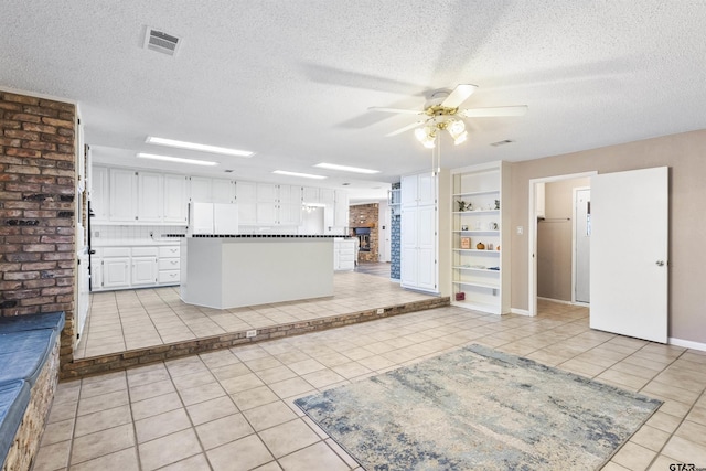 kitchen featuring white cabinetry, light tile patterned floors, a textured ceiling, and white refrigerator