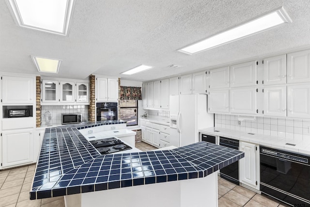 kitchen with light tile patterned flooring, white cabinetry, a center island, tile counters, and black appliances