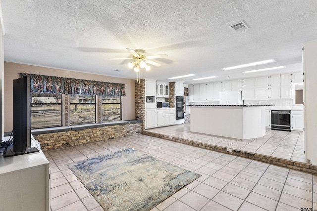 kitchen featuring white refrigerator, a center island, white cabinets, and beverage cooler