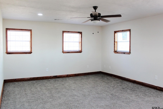 carpeted spare room featuring a healthy amount of sunlight and ceiling fan