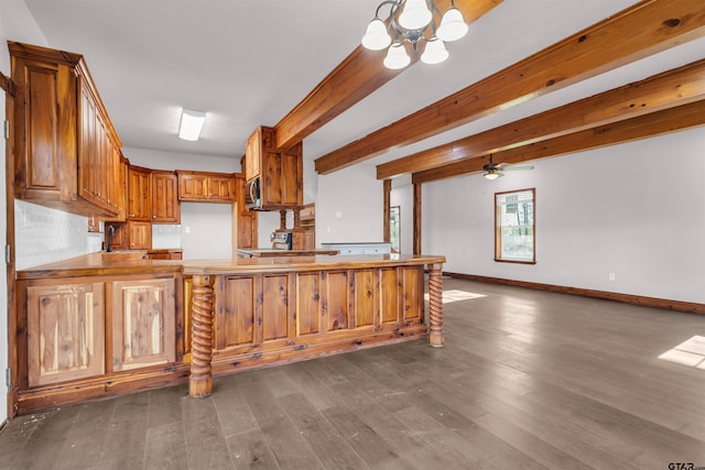 kitchen featuring a peninsula, baseboards, beam ceiling, appliances with stainless steel finishes, and a sink