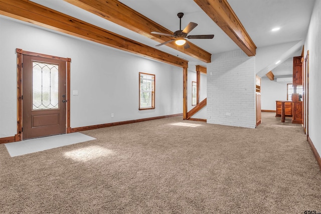 unfurnished living room featuring carpet flooring, a ceiling fan, beam ceiling, and a wealth of natural light