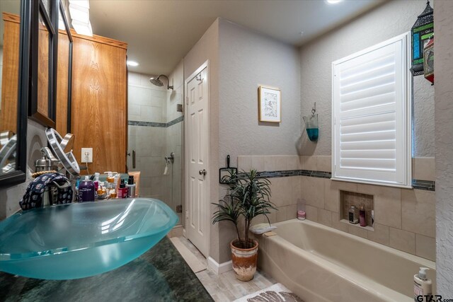 bathroom featuring shower with separate bathtub and sink