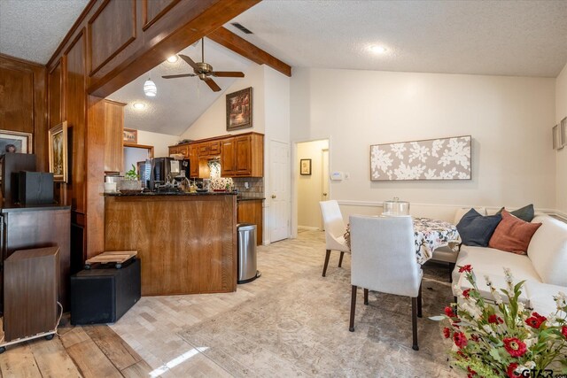 kitchen featuring kitchen peninsula, light wood-type flooring, backsplash, ceiling fan, and vaulted ceiling with beams