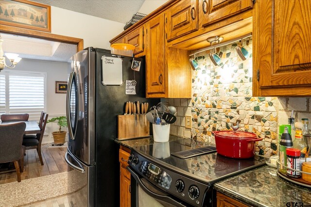 kitchen with black / electric stove, a textured ceiling, a chandelier, and backsplash