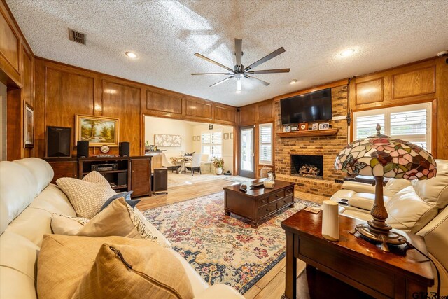 living room featuring a textured ceiling, ceiling fan, plenty of natural light, and a fireplace