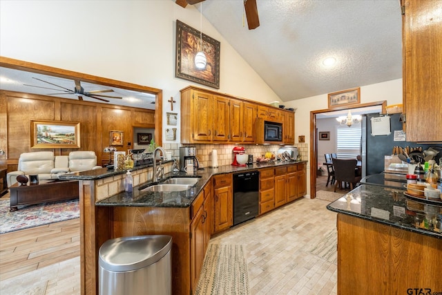 kitchen with sink, kitchen peninsula, ceiling fan with notable chandelier, black appliances, and a breakfast bar