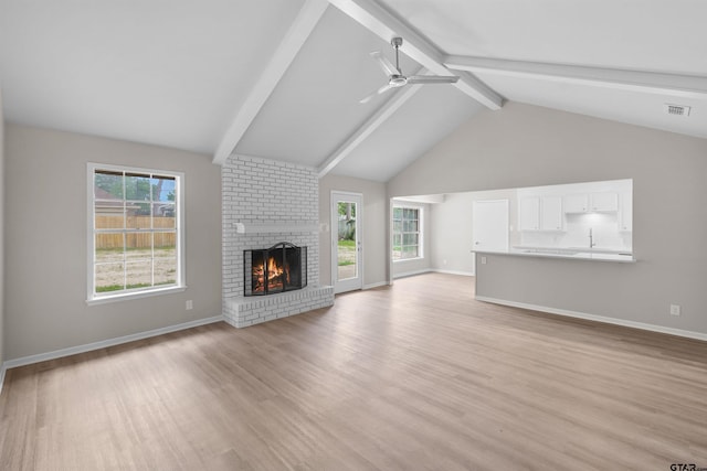 4816 Picadilly Pl, Tyler, TX 75703 - unfurnished living room featuring beam ceiling, a brick fireplace, light wood-type flooring, a ceiling fan, and baseboards