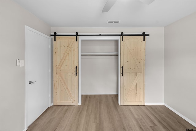 4816 Picadilly Pl, Tyler, TX 75703 - unfurnished bedroom with a barn door, wood finished floors, and baseboards