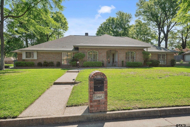 ranch-style home with a front yard, brick siding, and a shingled roof
