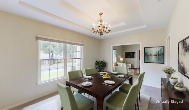 dining area with light colored carpet, a raised ceiling, and a notable chandelier