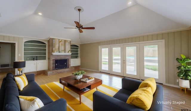 living room with a fireplace, built in features, light wood-type flooring, and vaulted ceiling