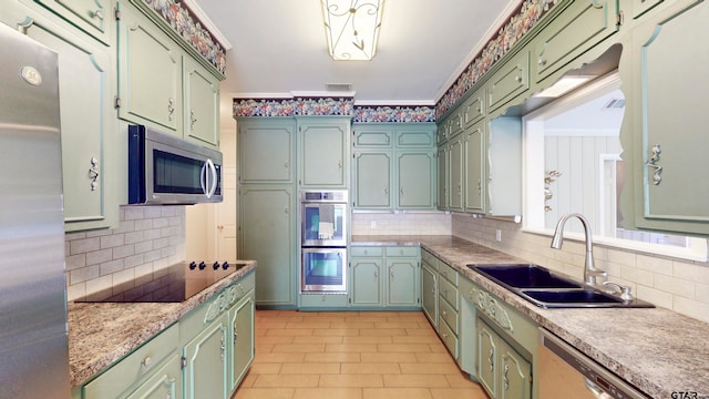 kitchen featuring ornamental molding, appliances with stainless steel finishes, green cabinets, decorative backsplash, and sink