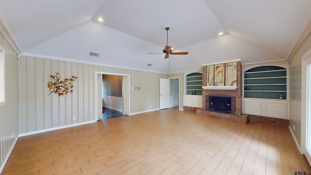 unfurnished living room featuring a fireplace, built in features, vaulted ceiling, and ornamental molding