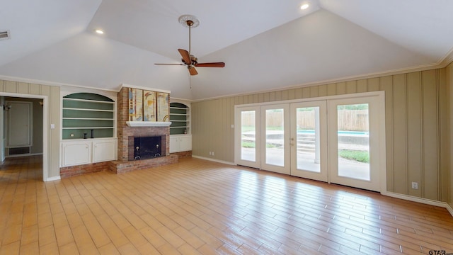 unfurnished living room featuring a brick fireplace, built in features, light wood-type flooring, and crown molding