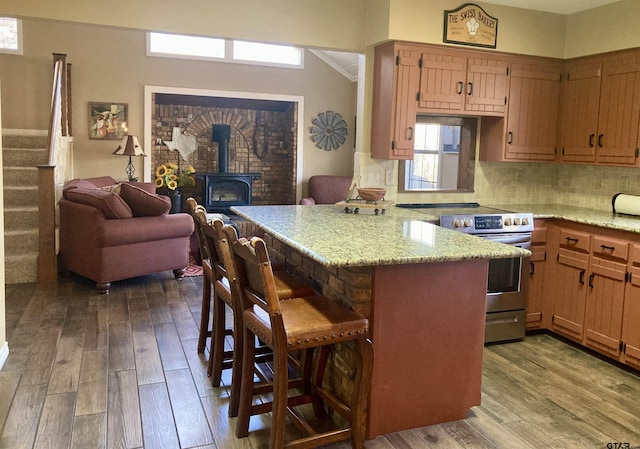 kitchen with stainless steel range with electric stovetop, a kitchen breakfast bar, kitchen peninsula, and light hardwood / wood-style floors