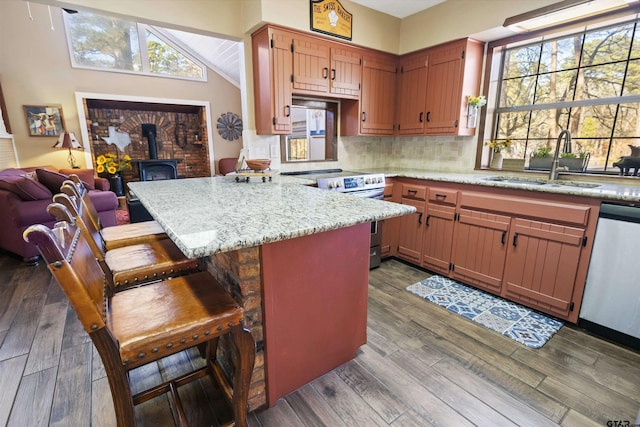 kitchen with a breakfast bar, sink, light stone counters, kitchen peninsula, and stainless steel appliances