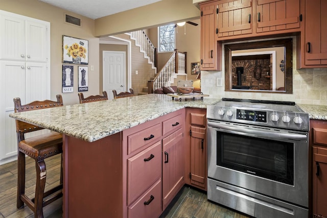 kitchen with stainless steel electric range oven, a kitchen breakfast bar, and kitchen peninsula