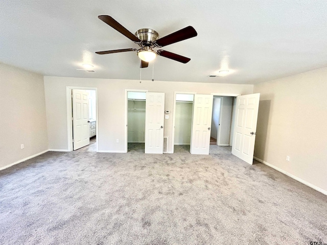 unfurnished bedroom featuring multiple closets, a ceiling fan, baseboards, and carpet flooring