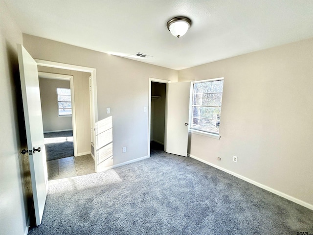 unfurnished bedroom with a closet, carpet, visible vents, and baseboards