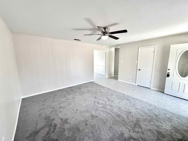 unfurnished bedroom featuring carpet floors, visible vents, a ceiling fan, tile patterned flooring, and baseboards