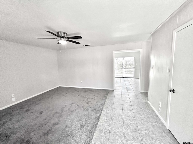 spare room with light carpet, light tile patterned floors, ceiling fan, and baseboards