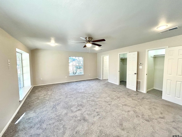 unfurnished bedroom featuring carpet, visible vents, and multiple closets