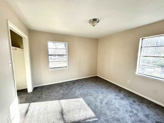 empty room with dark colored carpet and baseboards