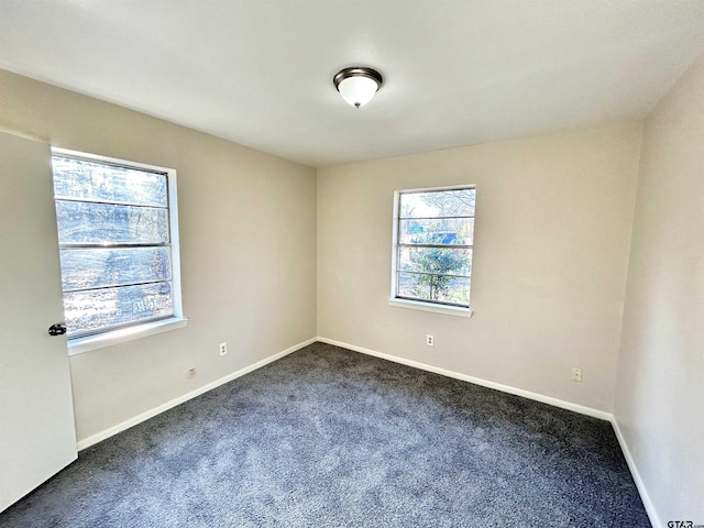 empty room with dark carpet and baseboards