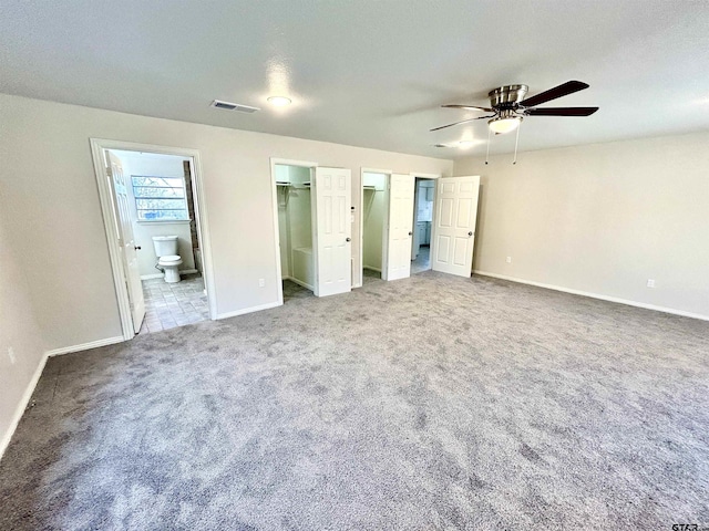 unfurnished bedroom featuring baseboards, visible vents, connected bathroom, a spacious closet, and carpet flooring