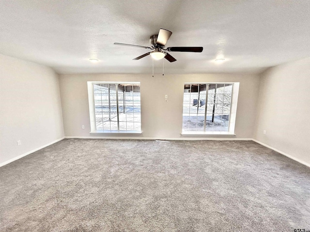 carpeted spare room with a healthy amount of sunlight, baseboards, a ceiling fan, and a textured ceiling