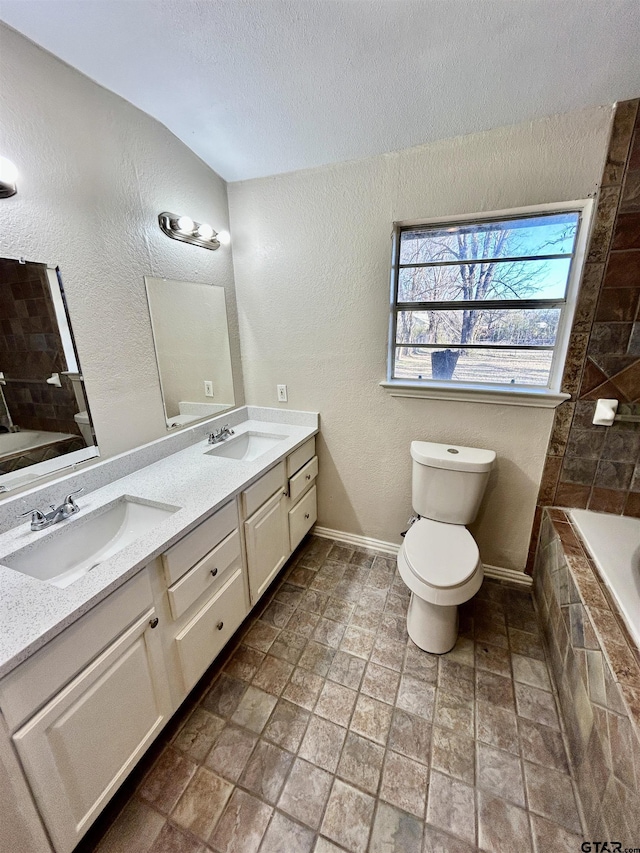 full bathroom featuring a relaxing tiled tub, a sink, baseboards, and double vanity