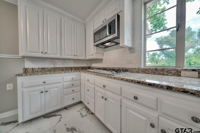 kitchen featuring stainless steel appliances, white cabinetry, tasteful backsplash, and dark stone counters