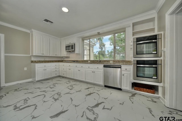 kitchen with light stone countertops, white cabinetry, stainless steel appliances, and ornamental molding