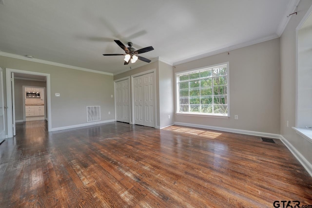 interior space featuring multiple closets, ceiling fan, dark hardwood / wood-style floors, and ornamental molding